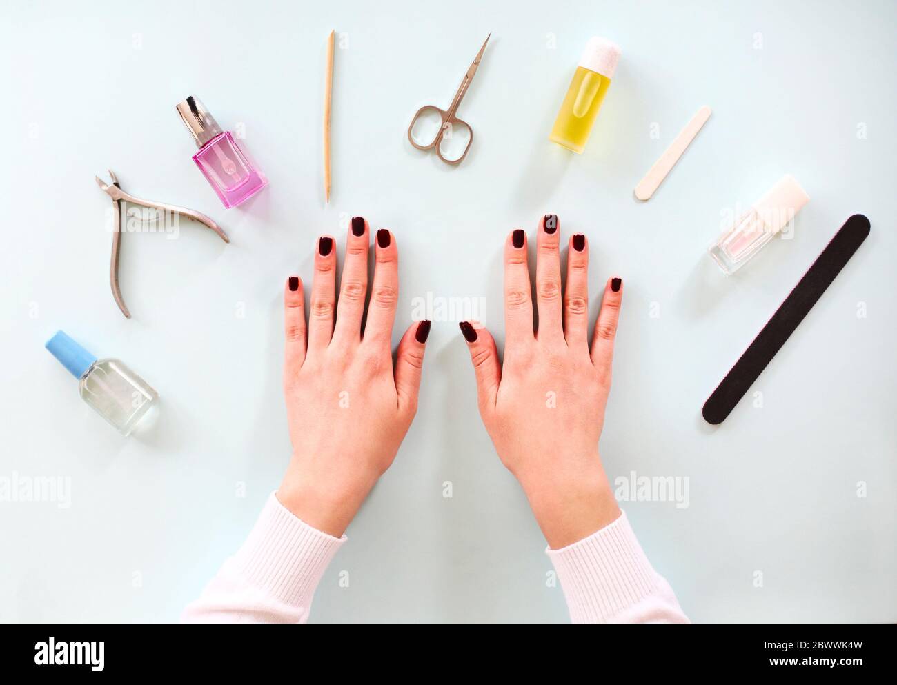 Vista superior de la cosecha mujer anónima con manicura oscura sentado en la mesa con varias herramientas durante el procedimiento de manicura profesional en el salón de spa Foto de stock