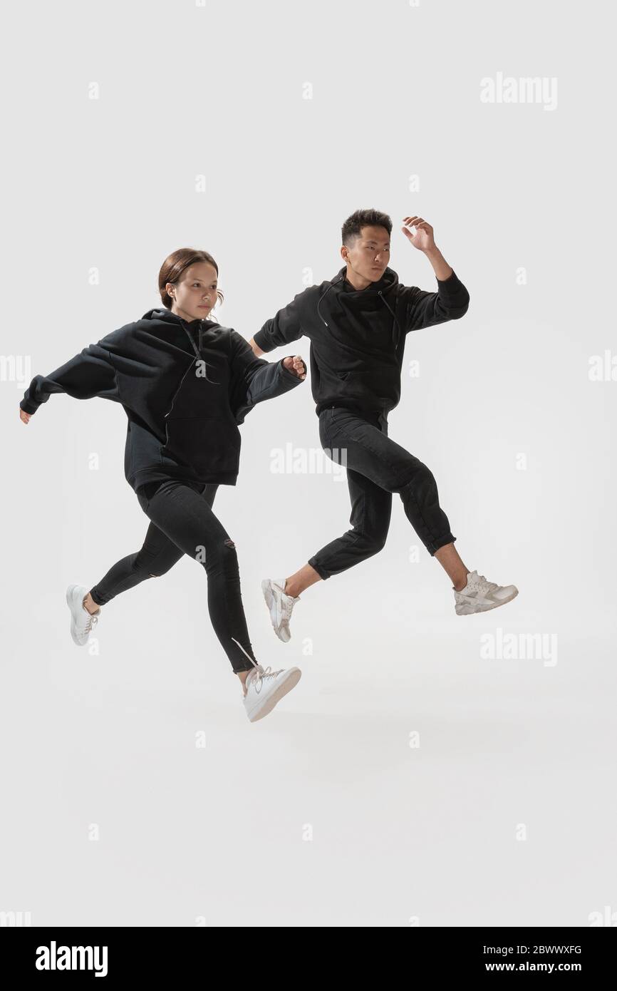 Correr a la libertad. Moderno pareja de moda aislado sobre fondo blanco  estudio. Mujer y hombre con estilo posando en ropa básica mínima igualmente  adecuado para ambos. Concepto de igualdad, inclusivo Fotografía