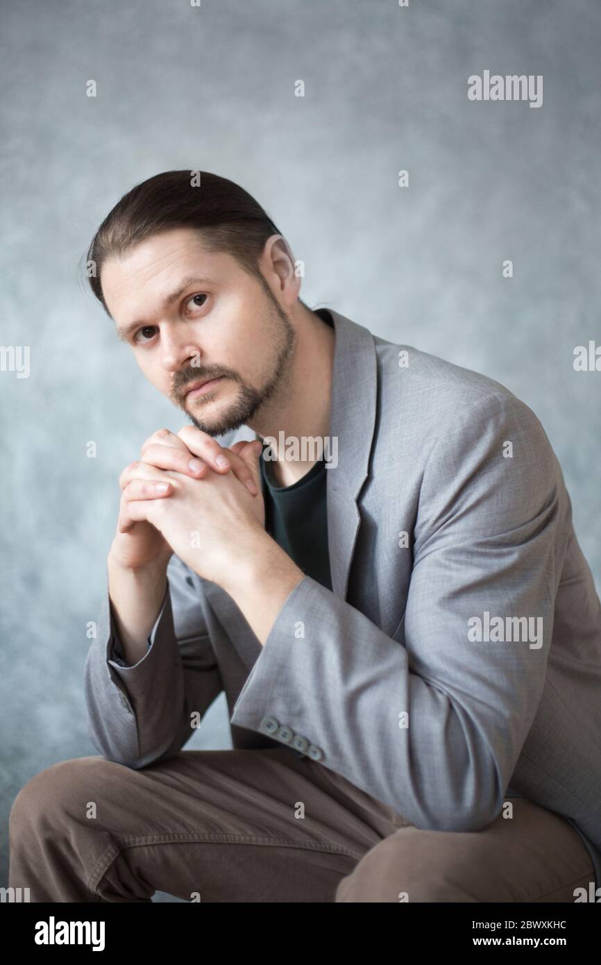 Retrato de un joven en una chaqueta de negocios sobre fondo gris en el estudio. Foto de stock