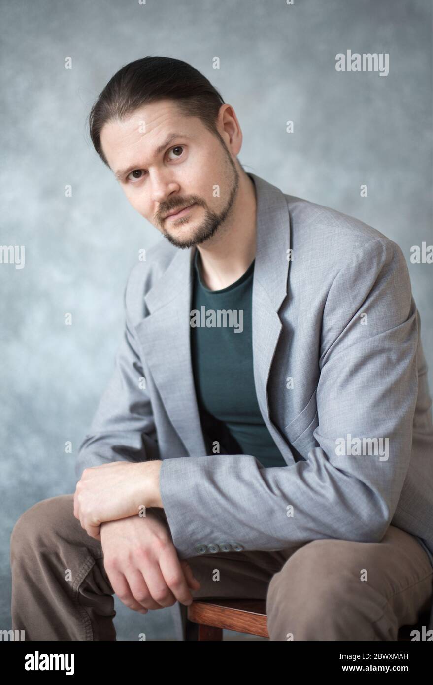 Retrato de un joven en una chaqueta de negocios sobre fondo gris en el estudio. Foto de stock