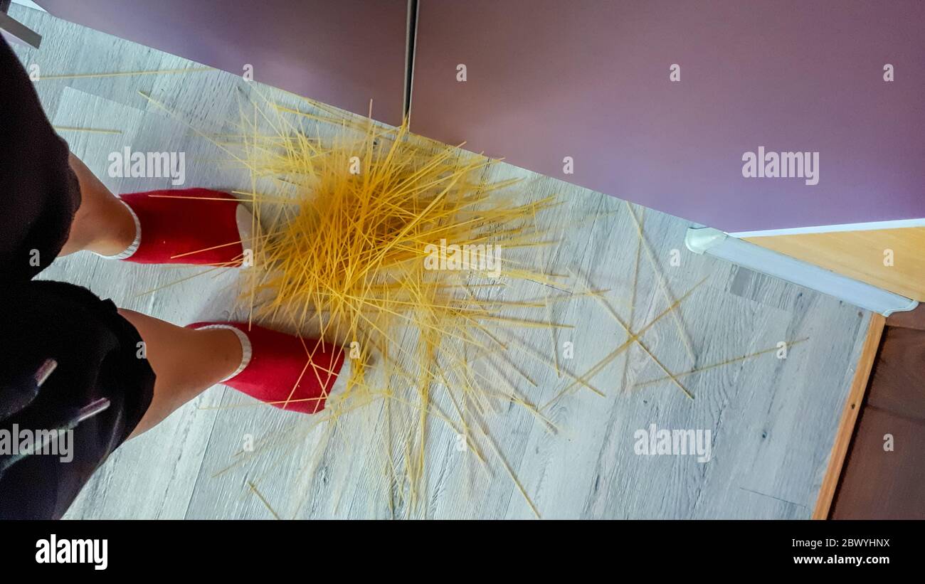Espaguetis esparcidos en el suelo. La mujer dejó caer el espagueti. Foto de stock