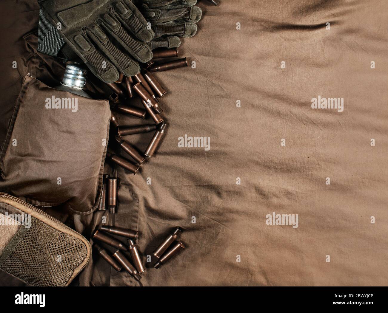 Foto de una mesa militar de superficie de tela con proyectiles de bala, guantes y vista superior de matraz. Foto de stock