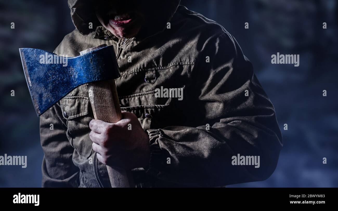 Foto de un aterrador asesino enojado hombre sosteniendo un hacha en el  fondo de madera oscura Fotografía de stock - Alamy
