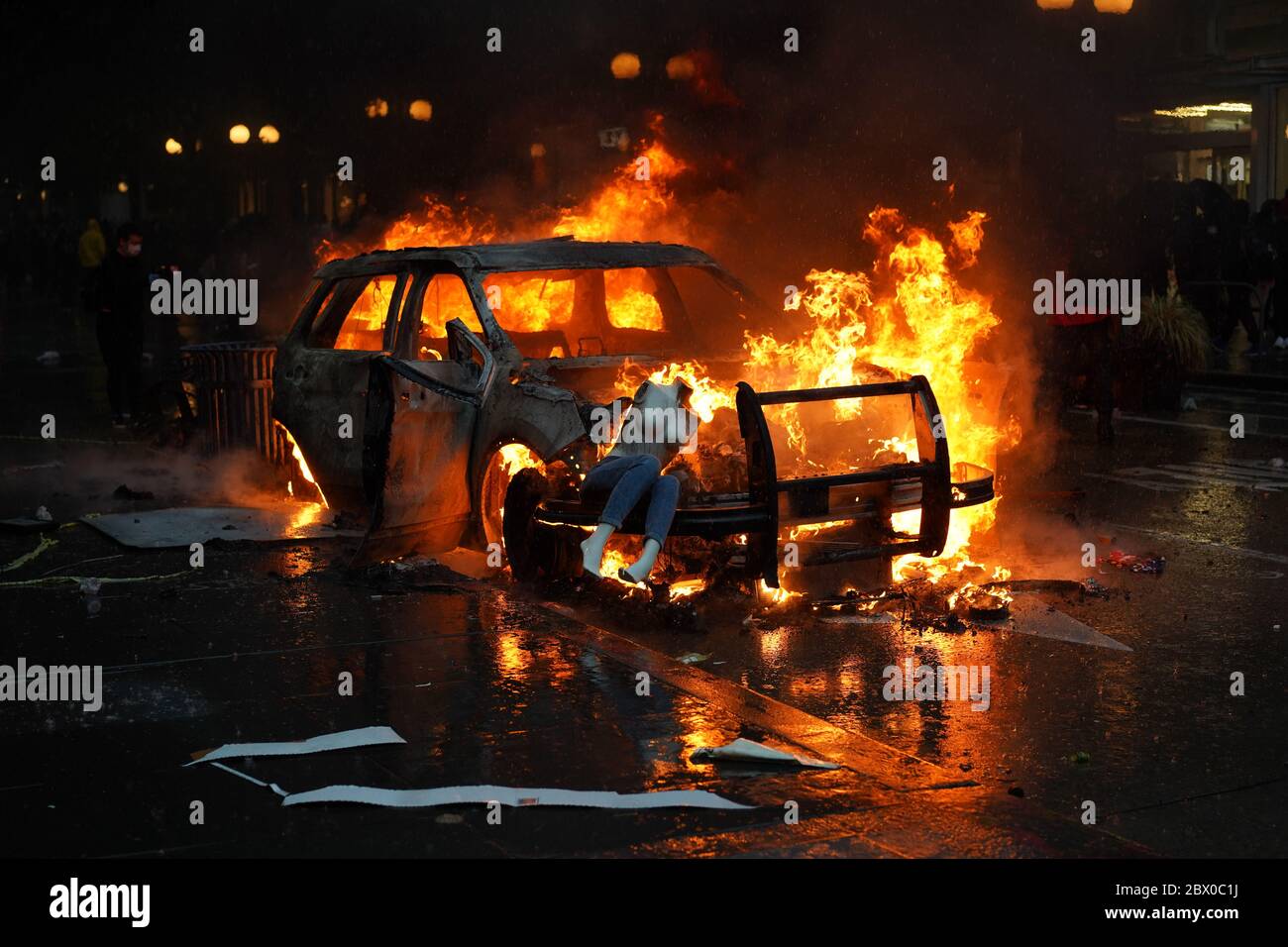 Un maniquí que fue saqueado de una tienda de ropa cercana se sienta encima de un coche de policía que fue incendiado durante las protestas de George Floyd en Seattle Foto de stock