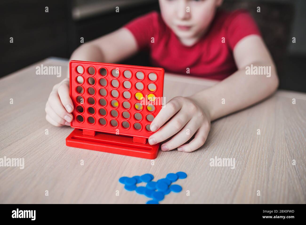 Juego de estrategia de tablero intelectual 'cuatro en una fila' - los niños juegan en la mesa Foto de stock