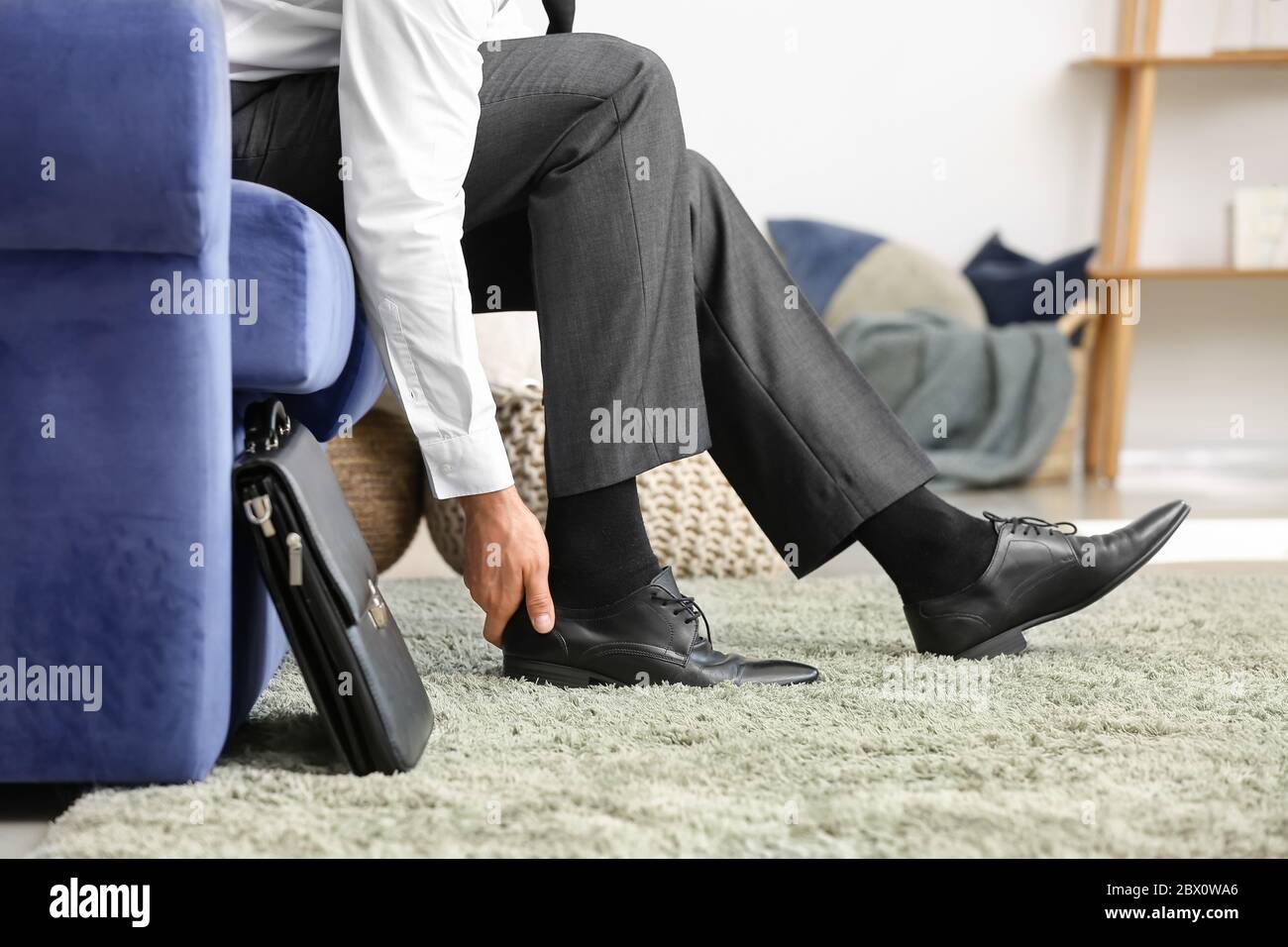 Hombre de negocios quitándose sus zapatos en casa después de un largo día  de trabajo Fotografía de stock - Alamy