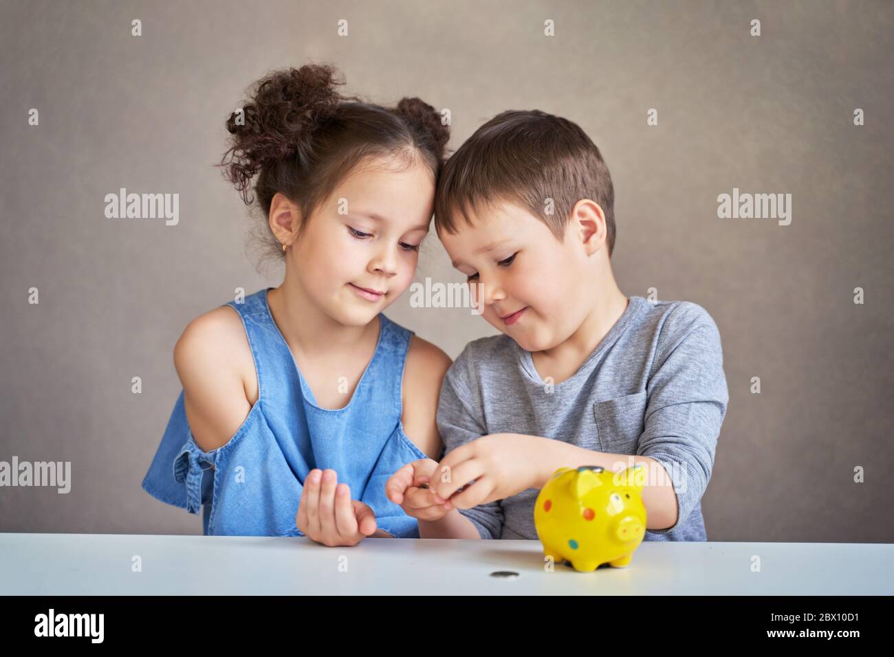 dos niños cuentan el dinero y lo ponen en una lechada Banco Foto de stock