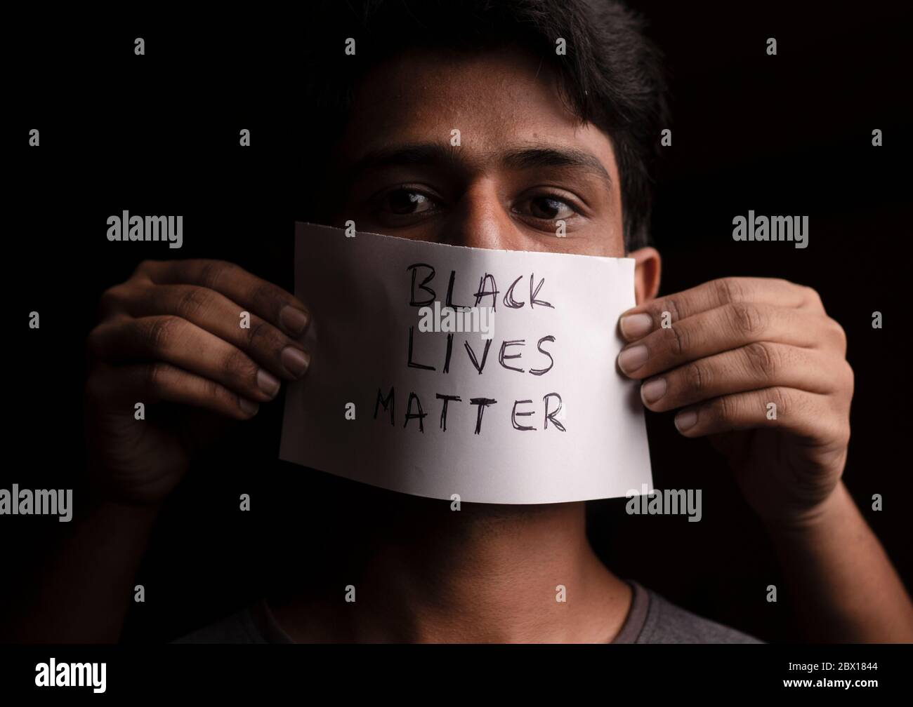 El rostro de un joven cubierto con vidas negras papel póster - concepto de discriminación racial contra la gente negra. Foto de stock