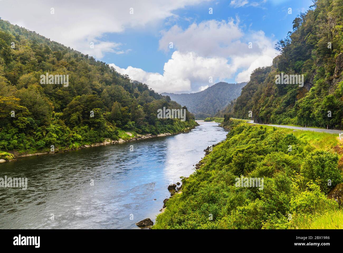 Río entre 2 verdes montañas boscosas en la isla sur de Nueva Zelanda Foto de stock