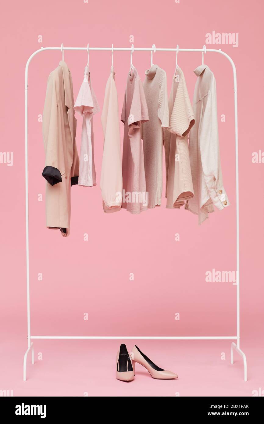 Imagen de los conjuntos de ropa colgando en percha con zapatos en el suelo  aislados sobre fondo rosa Fotografía de stock - Alamy