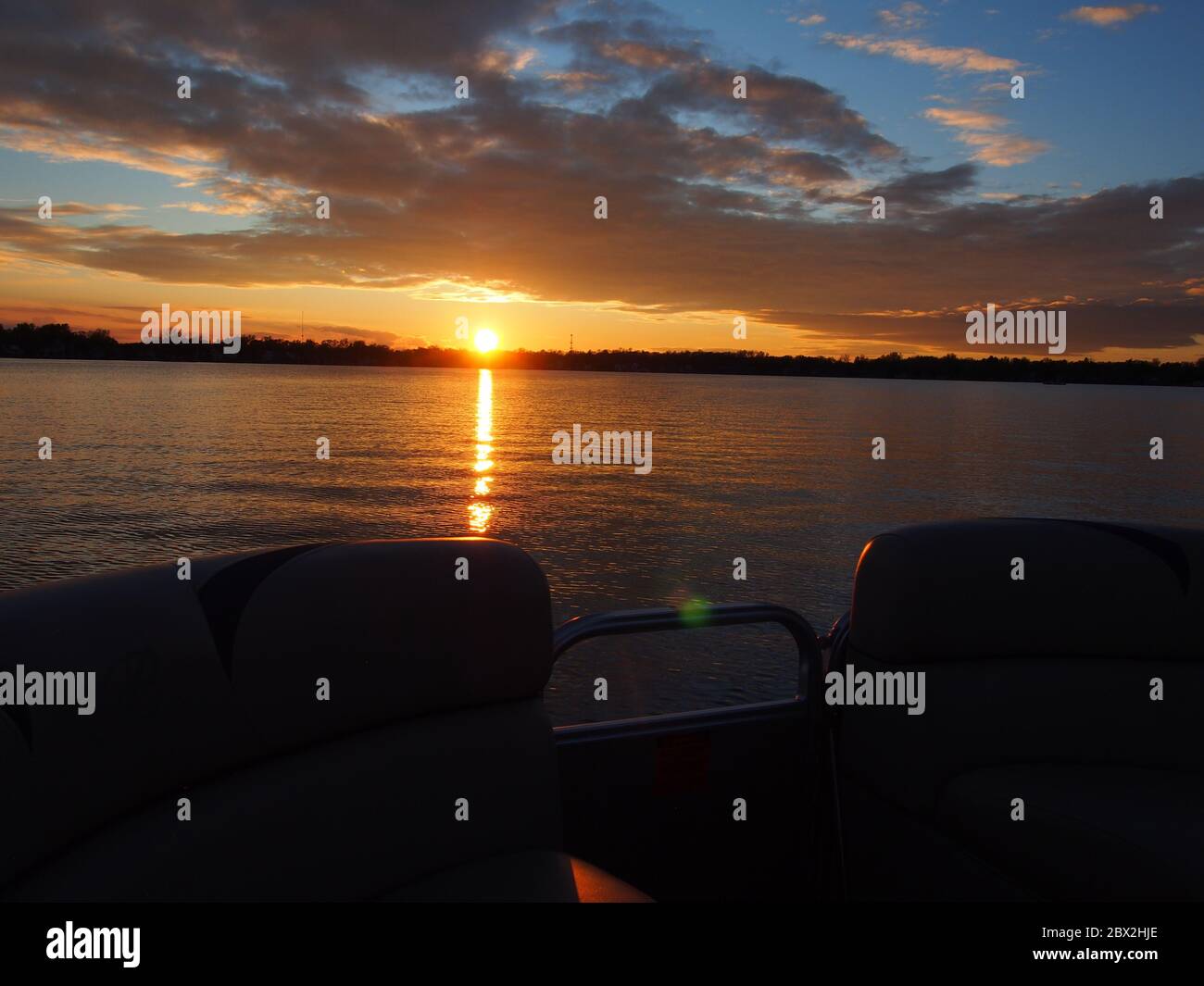 Puesta de sol en el lago que se refleja en el Pontoon Boat Foto de stock