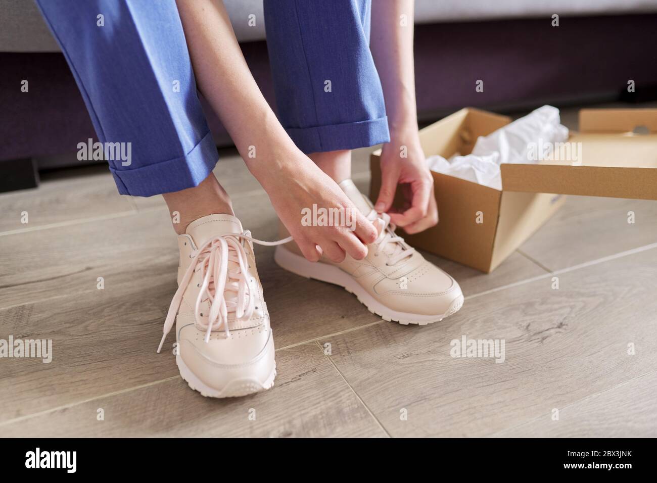 Primer plano de mujer piernas zapatos nuevas zapatillas, caja con zapatillas  de deporte en el fondo de la casa Fotografía de stock - Alamy