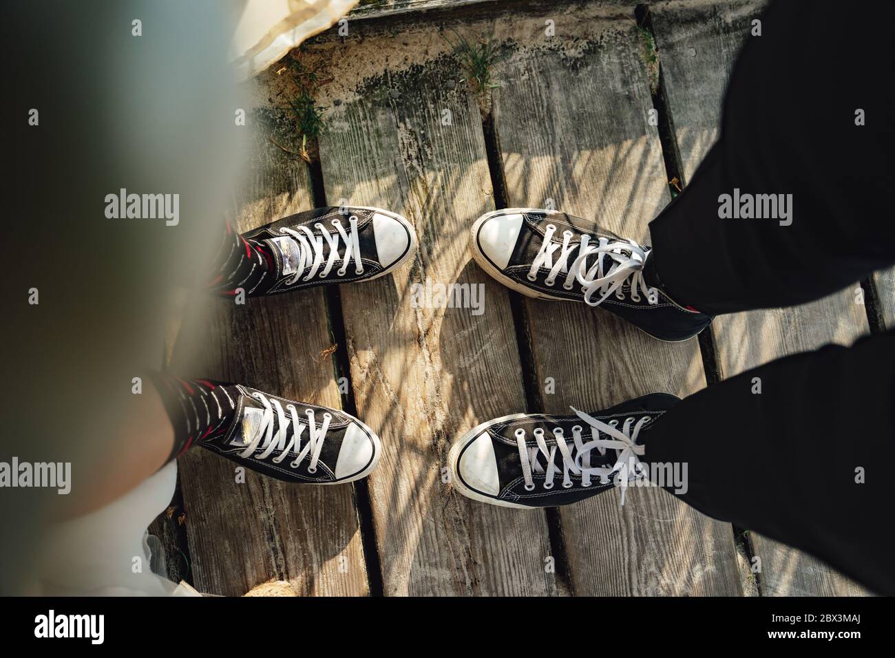 Dos pares de patas con zapatillas de deporte en blanco y negro en un paseo  marítimo de madera. Pareja de boda en zapatos informales Fotografía de  stock - Alamy