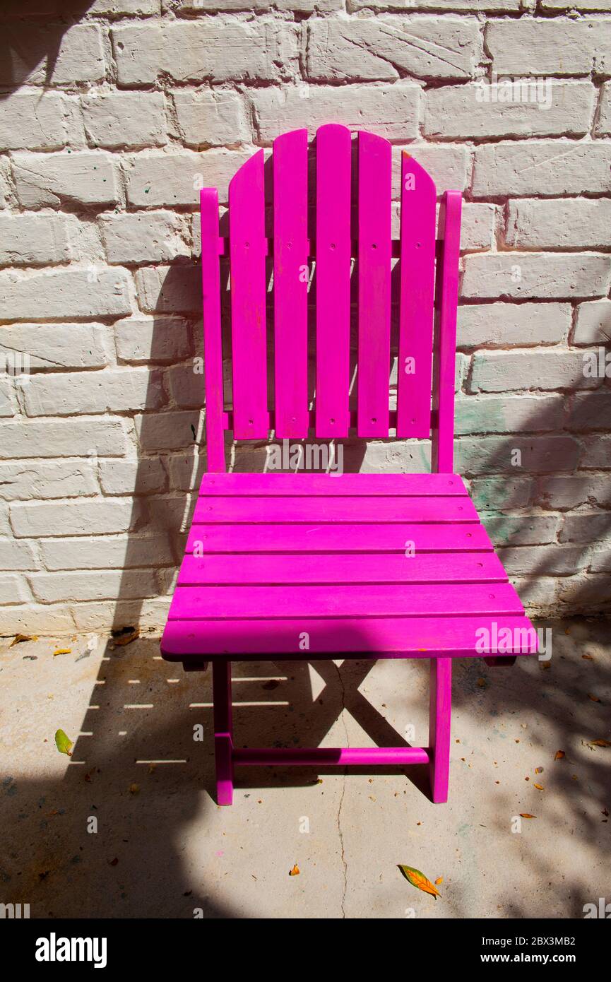 Silla plegable de madera rosa contra la pared de ladrillo blanco Fotografía  de stock - Alamy