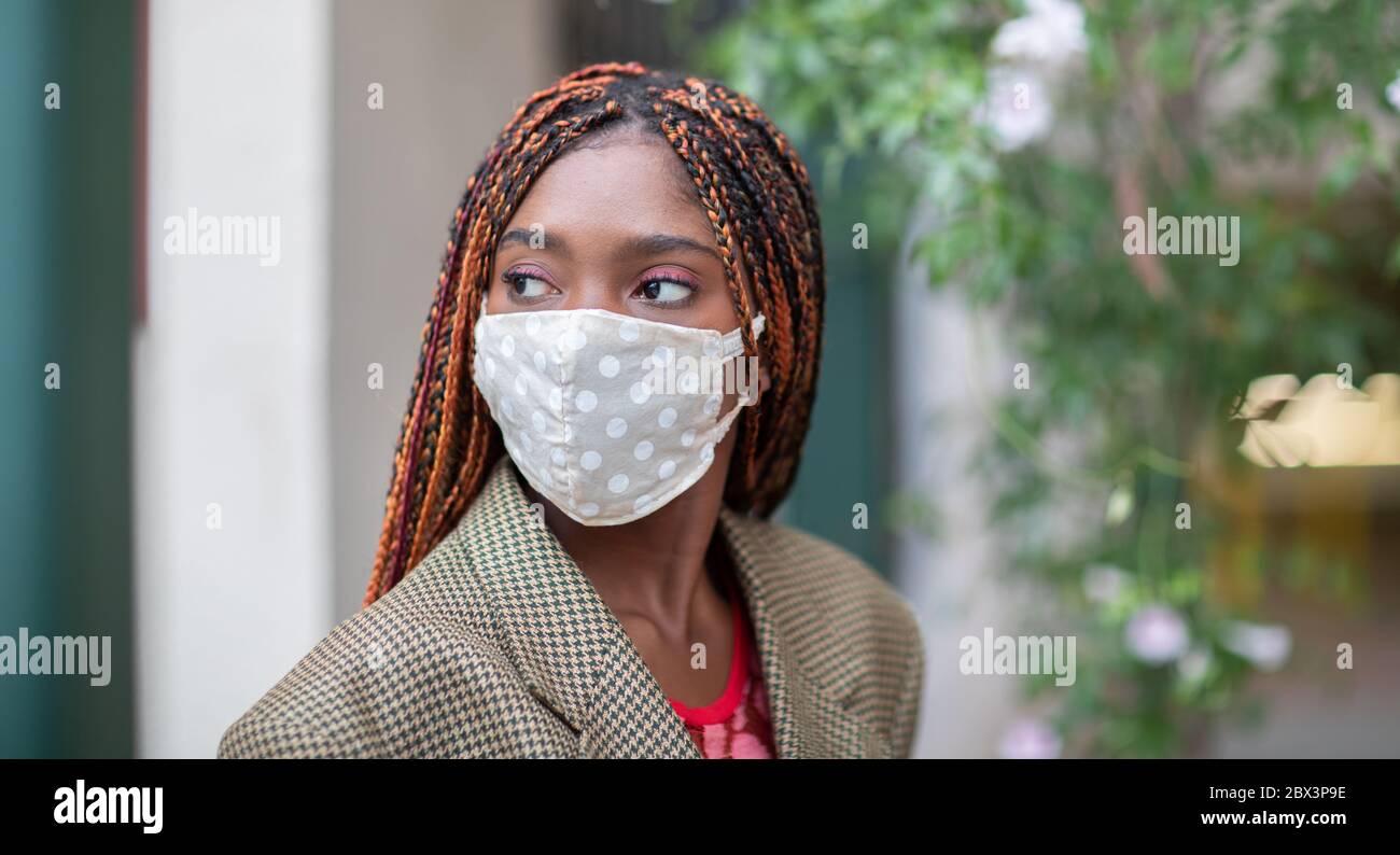 Niña de piel oscura con máscara protectora en la pandemia de coronavirus, COVID-19. Foto de stock