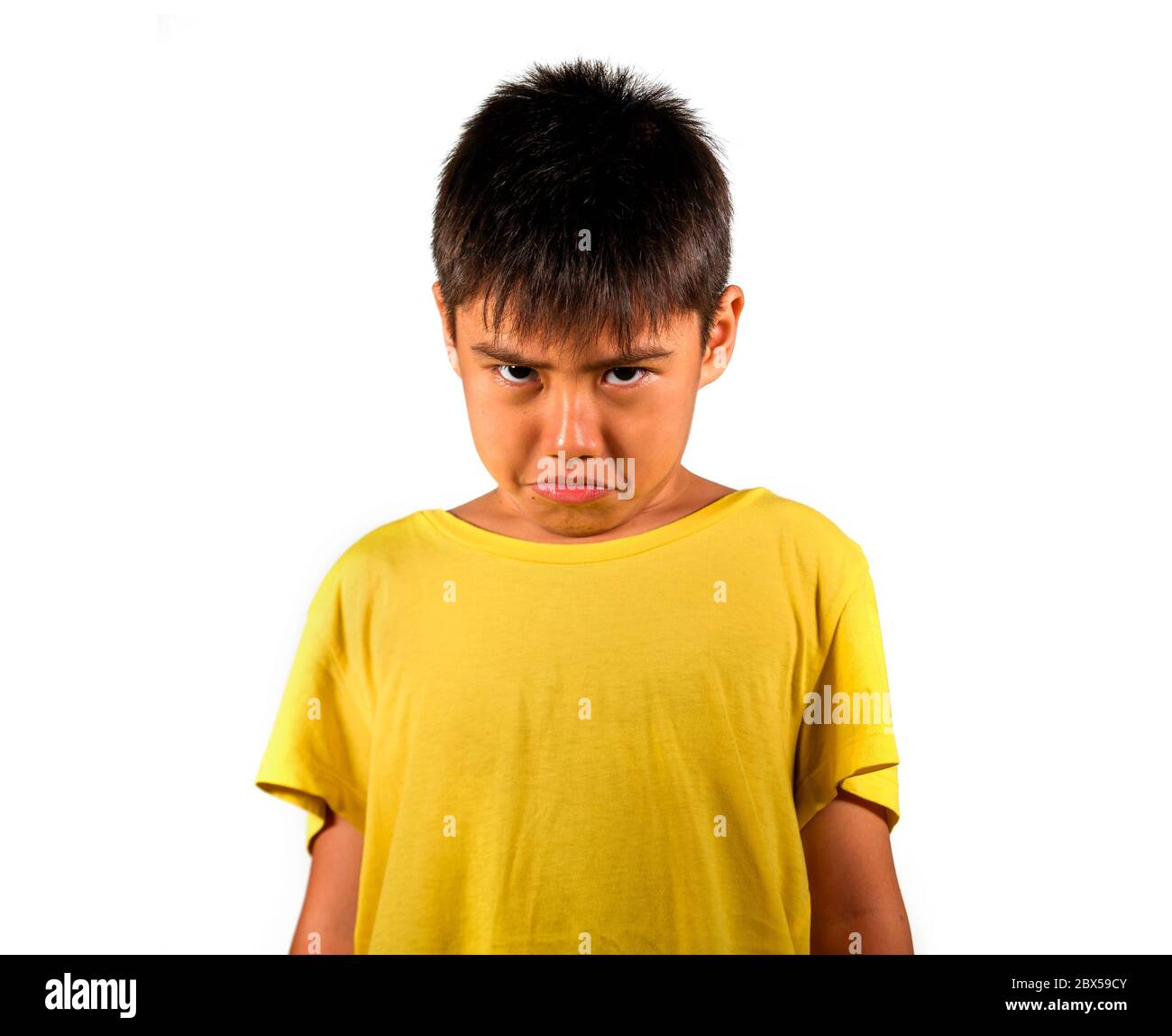 niño de 8 años triste y avergonzado después de sufrir reprimenda aislada sobre fondo blanco usando camiseta amarilla en niño emocional regañado y nagg Foto de stock