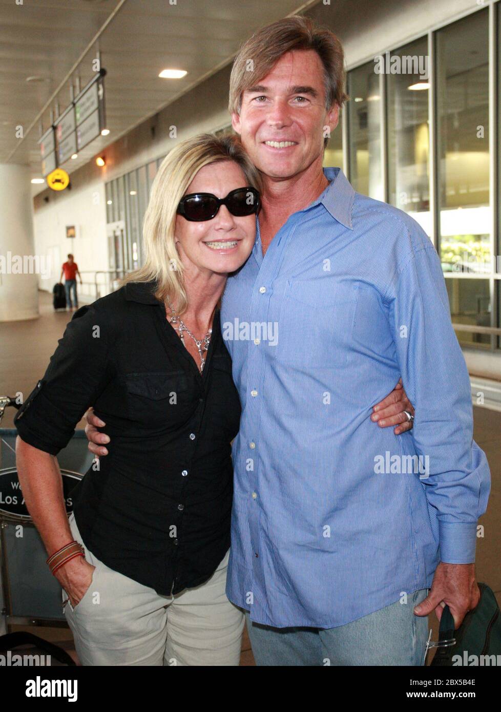 Olivia Newton-John y su marido llegan al Aeropuerto de los Ángeles después de unas vacaciones cortas en Florida. Olivia estaba resplandeciente y sonríe mientras se dirigía a casa. Agosto de 14 2008 Foto de stock