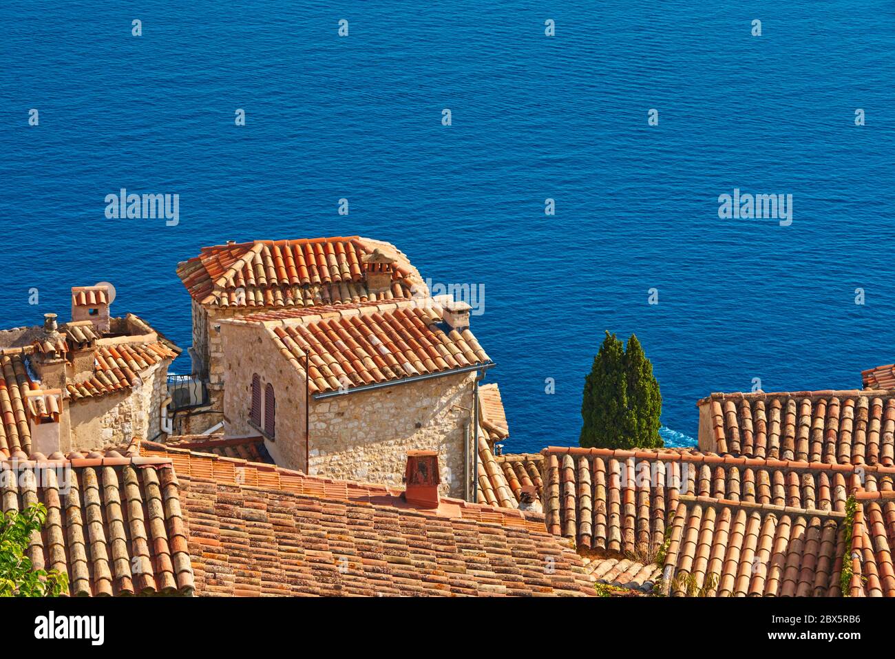 Tejados de terracota y campanario de la aldea de Eze con el mar Mediterráneo. Riviera Francesa, Alpes Marítimos (06), Francia Foto de stock