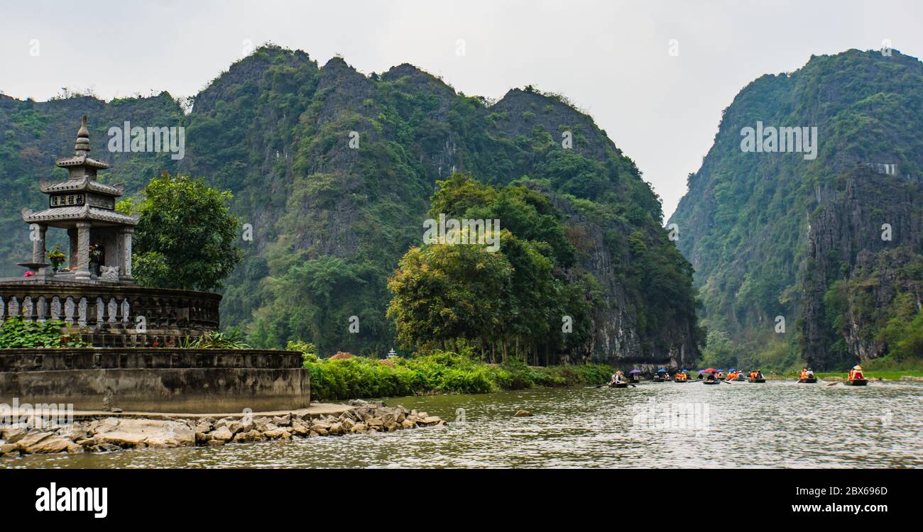 Viaje turístico a lo largo del río Tam Coc entre las montañas de piedra caliza en la zona de Ninh Binh, Vietnam Foto de stock