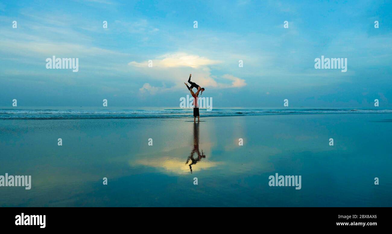 sano y atractivo ajuste pareja de acróbatas haciendo el equilibrio de la acroyoga y ejercicio de meditación en la hermosa playa del desierto practicando el equilibrio y la armonía Foto de stock