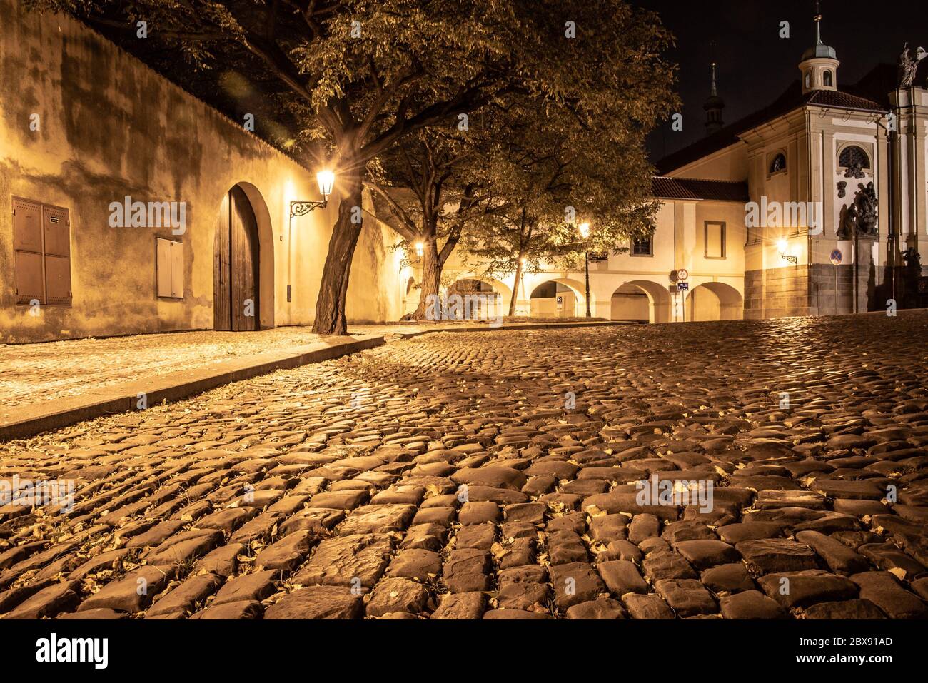 Calle adoquinada en la ciudad medieval antigua con casas iluminadas por lámparas de la calle de época, Novy Svet, Praga, República Checa. Foto nocturna. Foto de stock