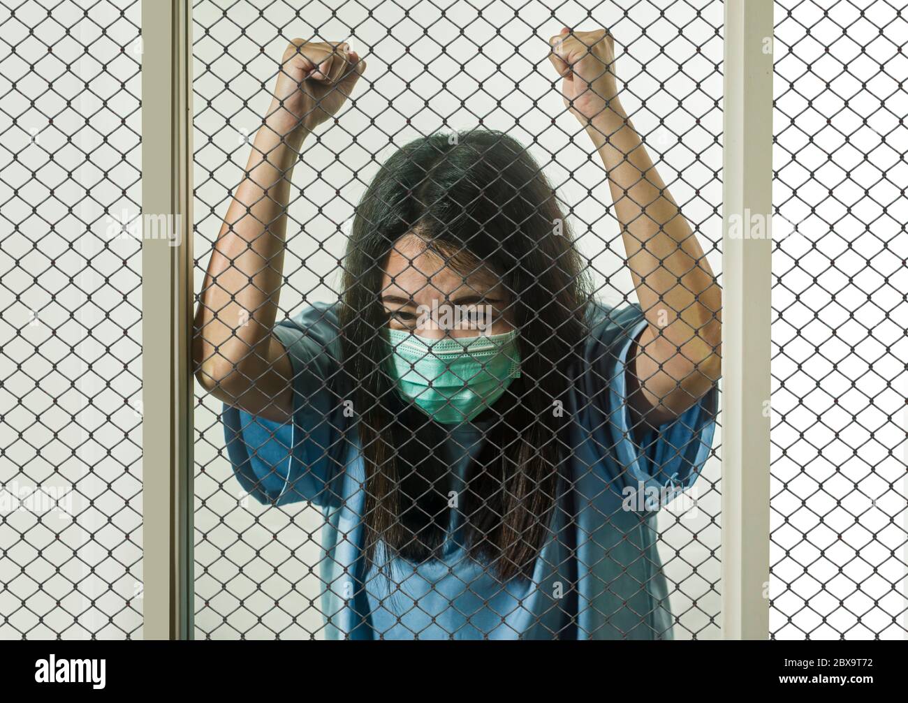 Retrato dramático de una joven China asiática infectada con virus víctima de enfermedades contagiosas o paciente psicótico e insano mental encerrado en el seur Foto de stock
