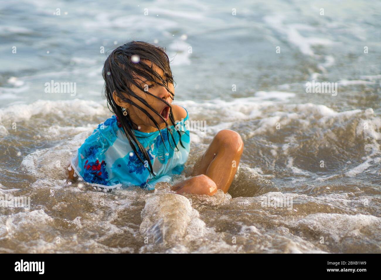 estilo de vida retrato franco de niña joven feliz y emocionada que se divierte en la playa nadando jugando con olas de mar disfrutando de una sensación de locura en libertad Foto de stock