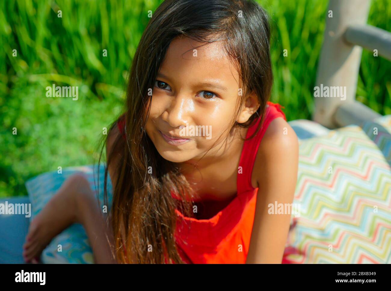 estilo de vida al aire libre retrato de hermosa y dulce niña sonriendo feliz y alegre el niño con ojos preciosos y vestido con un vestido rojo isola Foto de stock
