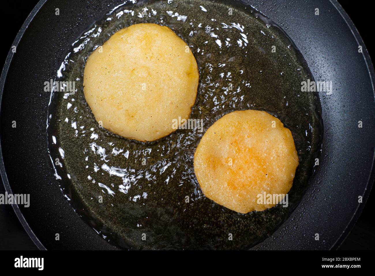 Arepas en una sartén con aceite. Vista superior. Cocina venezolana. Foto de stock