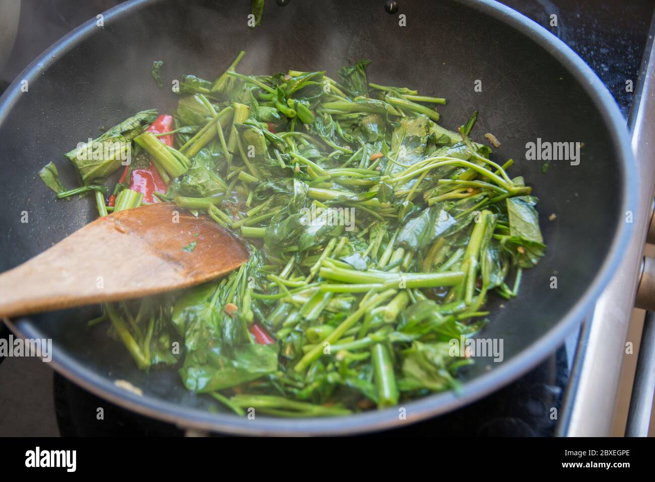 'Pad Pak Boong' un plato tradicional tailandés: Verduras 'Morning Glory' fritas (Ipomoea aquatica) a la parrilla en un wok Foto de stock