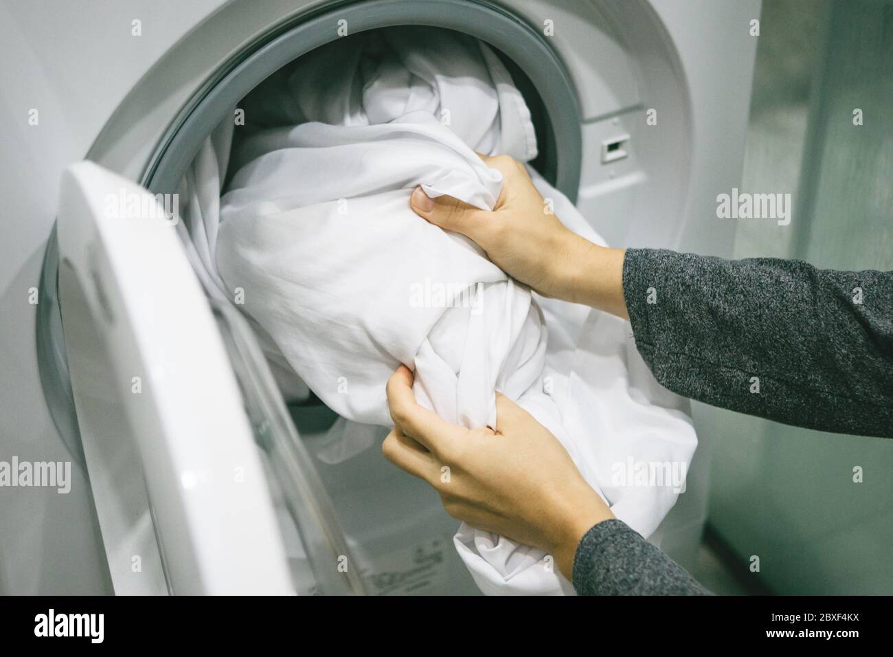 Una mujer o ama de casa carga o pone la ropa en el lavavajillas para lavar  Fotografía de stock - Alamy