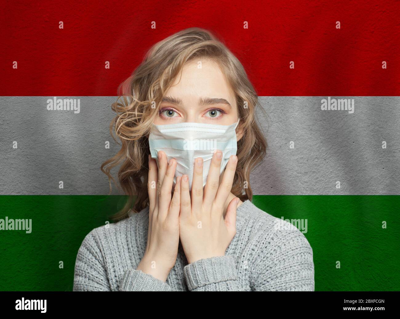 Mujer de pánico con una máscara en el fondo de la bandera de Hungría. Concepto de la epidemia de gripe y la protección contra virus Foto de stock