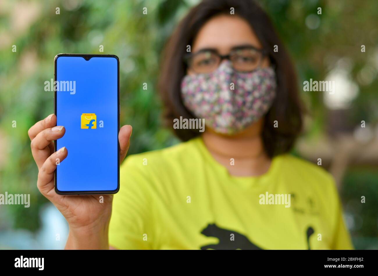 Nueva Delhi, India, 2020. Chica que lleva máscara mostrar Flipkart aplicación en el móvil bajo cuarentena en el hogar durante la pandemia de la enfermedad del virus de la Corona (Covid-19). Solo deliv Foto de stock