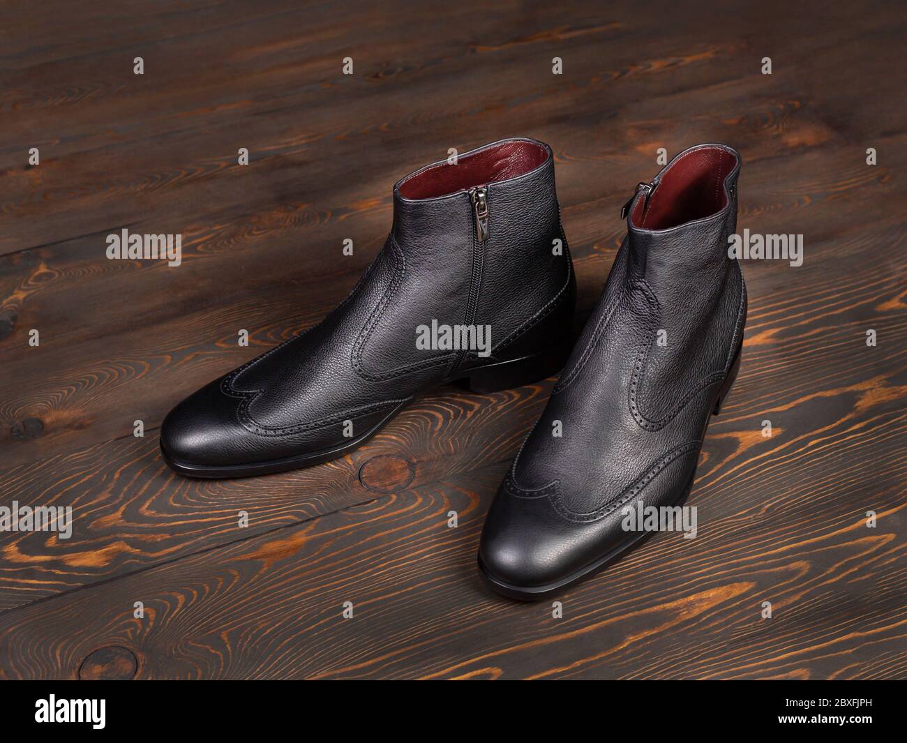 Un par de botas clásicas para el tobillo de hombre hechas de piel negra  sobre un fondo de madera de tablas. Vista lateral de primer plano  Fotografía de stock - Alamy