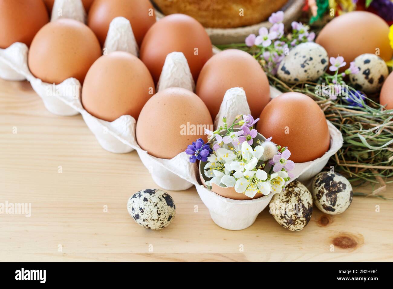 Huevos en caja de papel y decoraciones de Pascua con flores. Tiempo festivo Foto de stock
