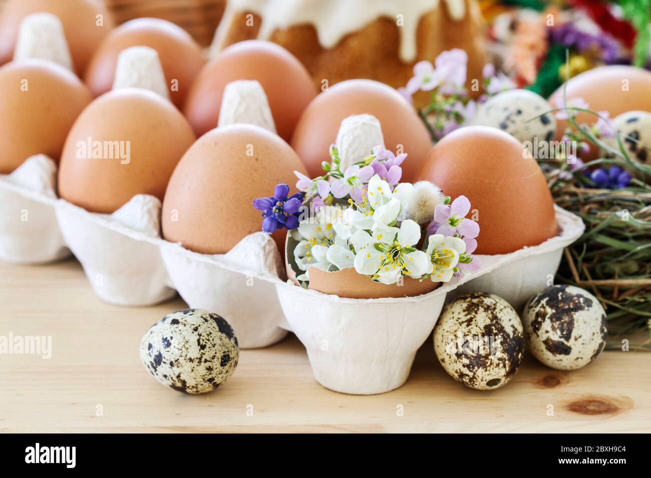 Huevos en caja de papel y decoraciones de Pascua con flores. Tiempo festivo Foto de stock