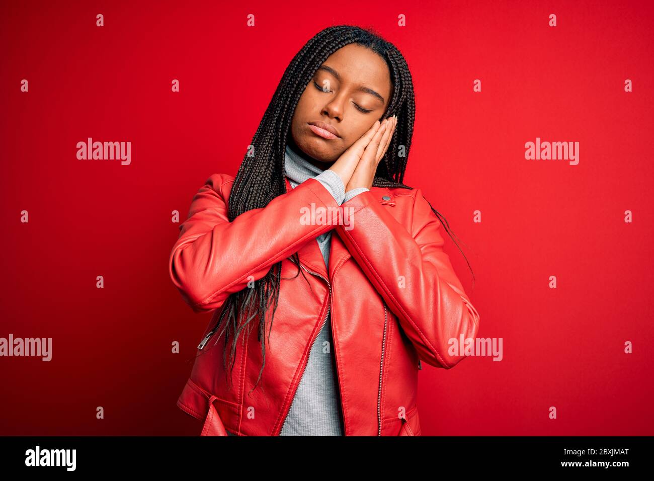 Joven afroamericana con chaqueta de cuero de moda sobre rojo aislado fondo  dormir cansado soñar y posar con las manos juntas w Fotografía de stock -  Alamy