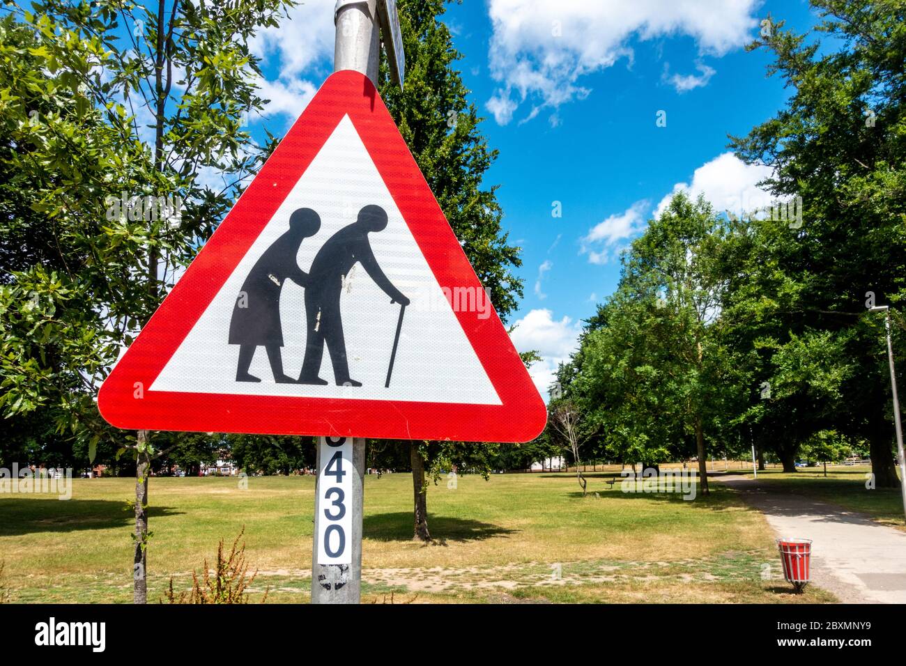 Un signo triangular rojo en un parque advierte a las personas de peatones que pueden ser lentos o inestables debido a la vejez o a la falta de firmeza. Foto de stock