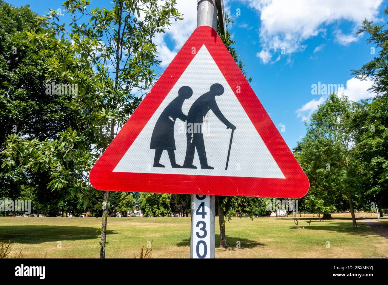 Un signo triangular rojo en un parque advierte a las personas de peatones que pueden ser lentos o inestables debido a la vejez o a la falta de firmeza. Foto de stock