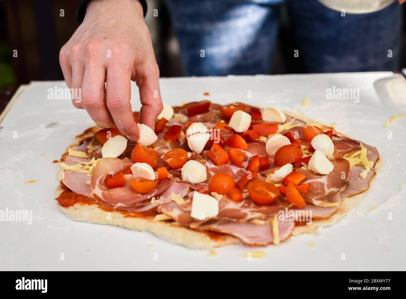 Elaboración de pizza casera italiana en horno de ladrillo chimenea. Hacer  pizza y añadir diferentes ingredientes antes de hornearla en la chimenea  exterior. Mano Fotografía de stock - Alamy