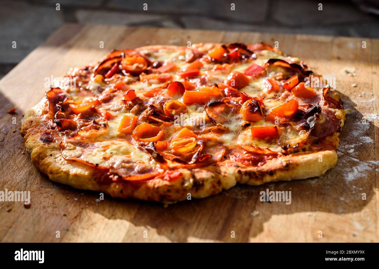 Elaboración de pizza casera italiana en horno de ladrillo chimenea.  Elaboración de pizza tradicional en chimenea de ladrillo de piedra con leña  y carbones. Acabado de la Tast Fotografía de stock -