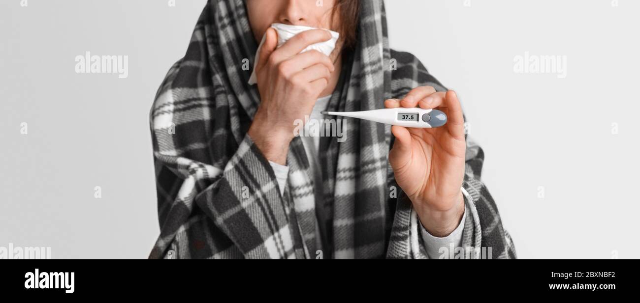 Fiebre y enfermedad. El hombre tose, cubre la boca con servilleta y muestra un termómetro con alta temperatura Foto de stock