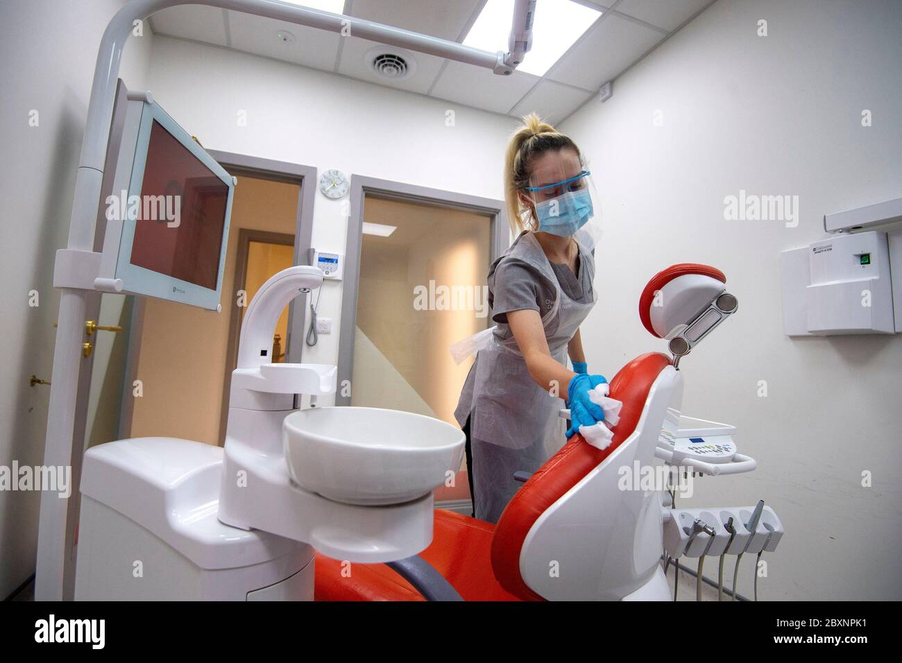 La enfermera dental Charlie Coppen limpia la sala de examen después de tratar a un paciente en Woodford Dental Care en el norte de Londres, ya que la práctica se abre por primera vez desde que el Reino Unido entró en el bloqueo coronavirus. Foto de stock