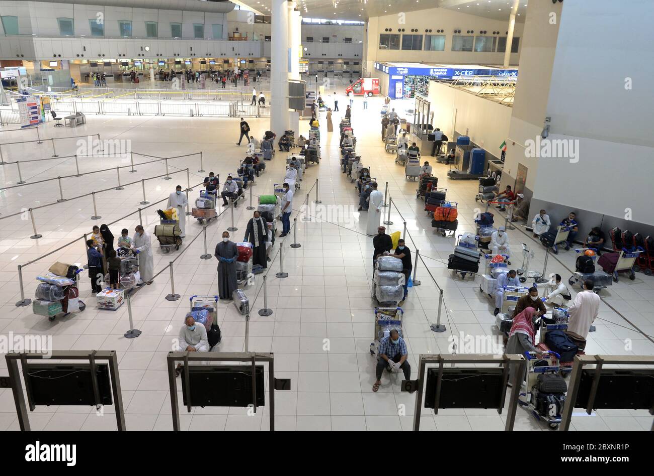 Gobernación de Farwaniya, Kuwait. 8 de junio de 2020. Pasajeros egipcios esperan en la sala de salida del Aeropuerto Internacional de Kuwait durante una operación de repatriación en la provincia de Farwaniya, Kuwait, 8 de junio de 2020. Kuwait planea reanudar los vuelos comerciales en tres etapas, dijo el domingo el Ministro de Estado de Asuntos de Servicios y el Ministro de Estado de Asuntos de la Asamblea Nacional Mubarak al-Harees. Cabe señalar que el aeropuerto de Kuwait ha estado trabajando conjuntamente con los ministerios pertinentes para repatriar a residentes extranjeros que esperan volver a casa, dijo el ministro. El 13 de marzo, Kuwait suspe crédito: Xin Foto de stock