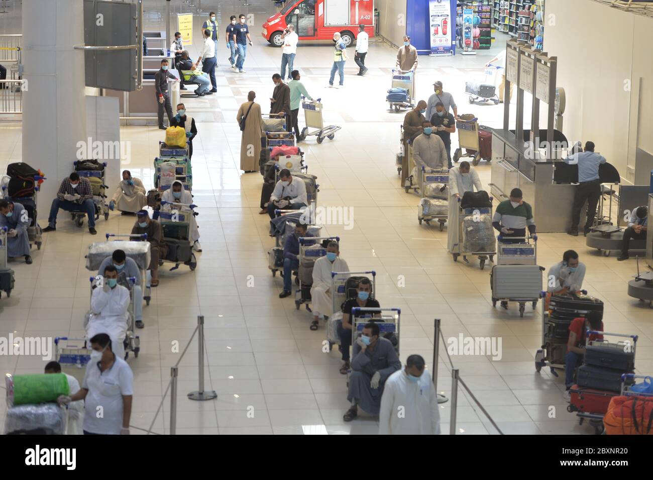 Gobernación de Farwaniya, Kuwait. 8 de junio de 2020. Pasajeros egipcios esperan en la sala de salida del Aeropuerto Internacional de Kuwait durante una operación de repatriación en la provincia de Farwaniya, Kuwait, 8 de junio de 2020. Kuwait planea reanudar los vuelos comerciales en tres etapas, dijo el domingo el Ministro de Estado de Asuntos de Servicios y el Ministro de Estado de Asuntos de la Asamblea Nacional Mubarak al-Harees. Cabe señalar que el aeropuerto de Kuwait ha estado trabajando conjuntamente con los ministerios pertinentes para repatriar a residentes extranjeros que esperan volver a casa, dijo el ministro. El 13 de marzo, Kuwait suspe crédito: Xin Foto de stock