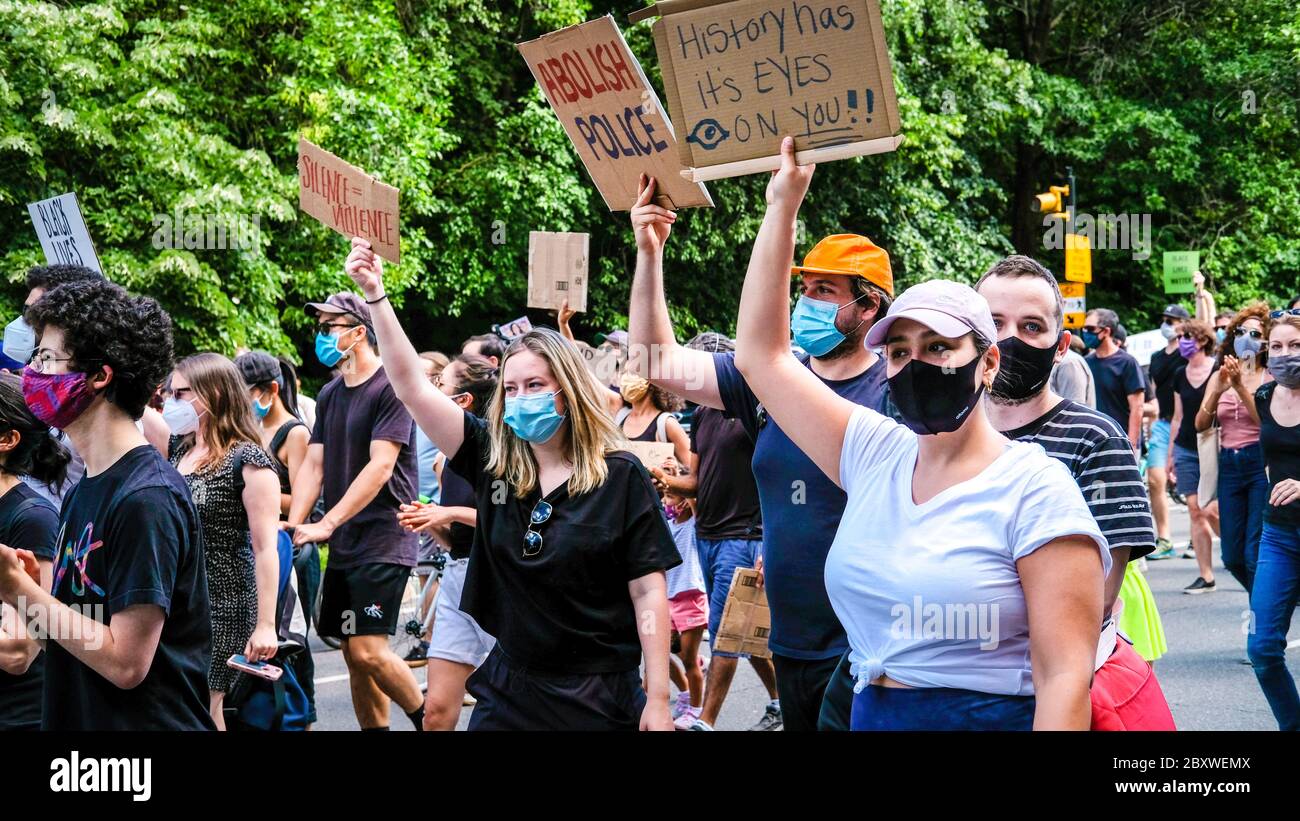 Manifestantes que llevaban máscaras con señales de protesta en una marcha en Brookyn Foto de stock