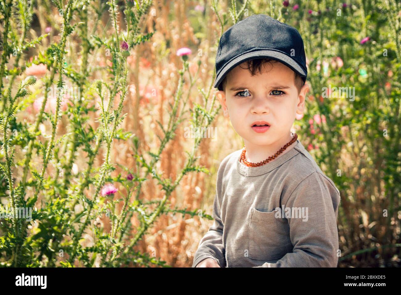 Lindo niño pequeño en gorra negra de béisbol y collar de ámbar en su cuello al libre Fotografía de stock - Alamy