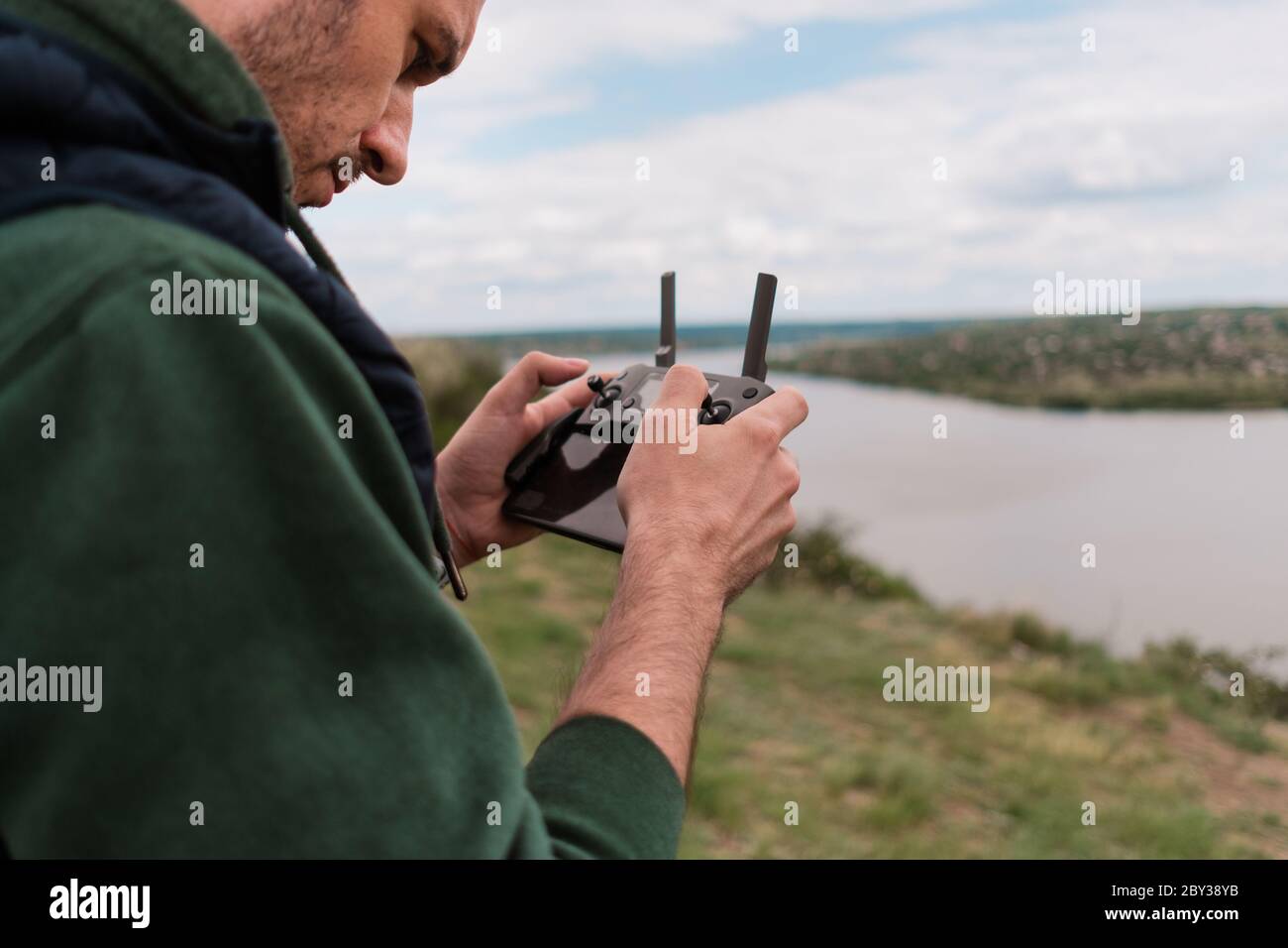 Joven hombre pilotando drones al aire libre en la naturaleza. Hombre que prueba el vehículo aéreo no tripulado en la naturaleza. Telón de fondo para entretenimiento de adultos Foto de stock