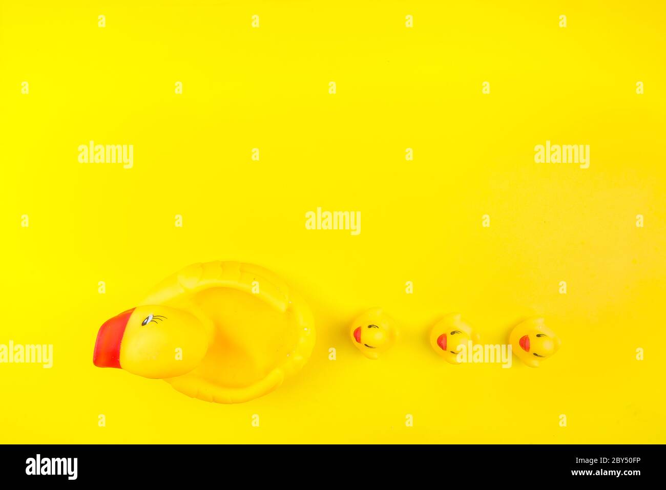 Juguete de goma de color amarillo Mama pato y pequeños patitos sobre un fondo amarillo. El concepto de atención materna y amor a los niños. Plano, tapa Foto de stock