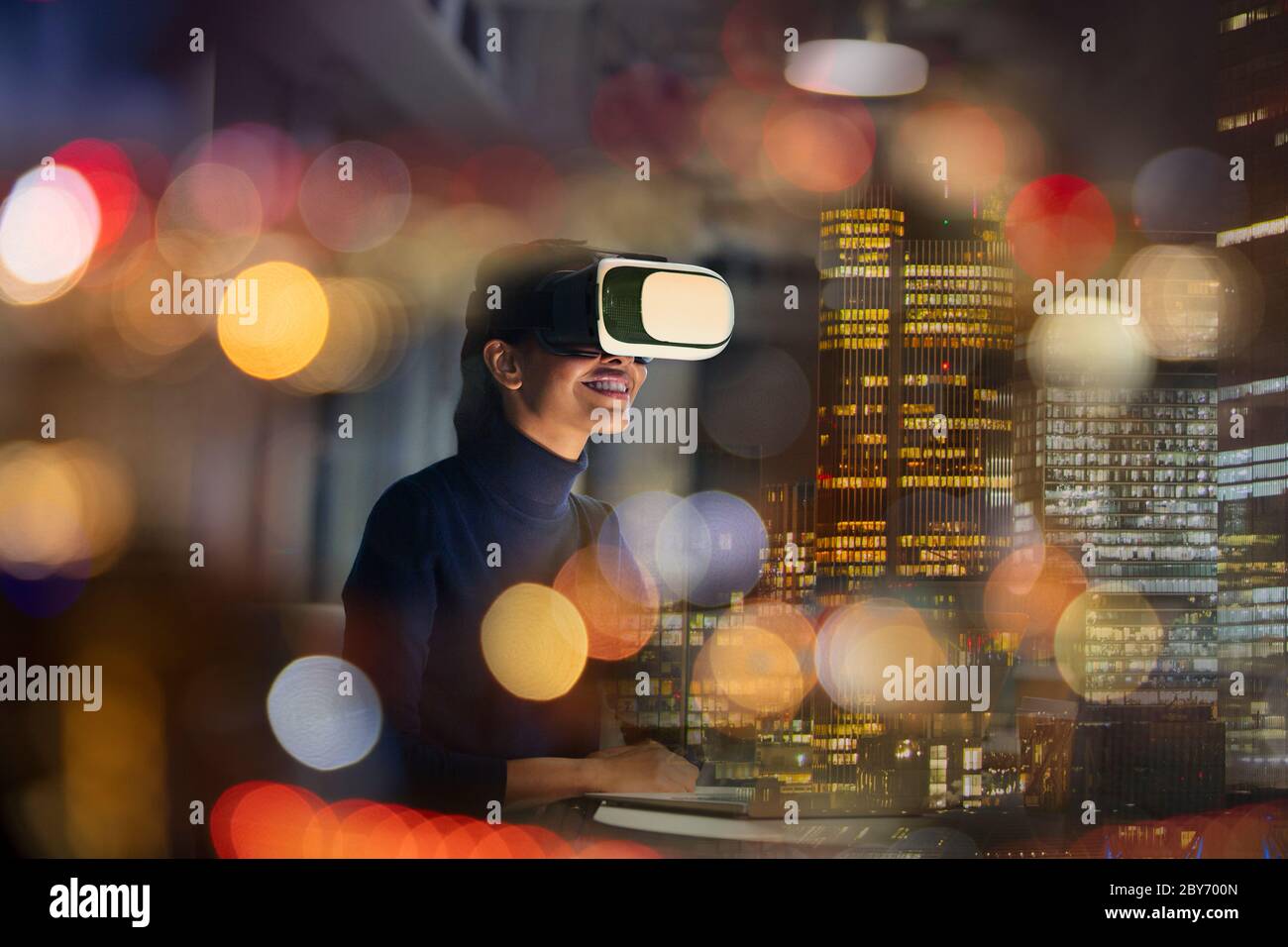 Mujer de negocios con gafas de realidad virtual en la oficina de gran altura por la noche Foto de stock